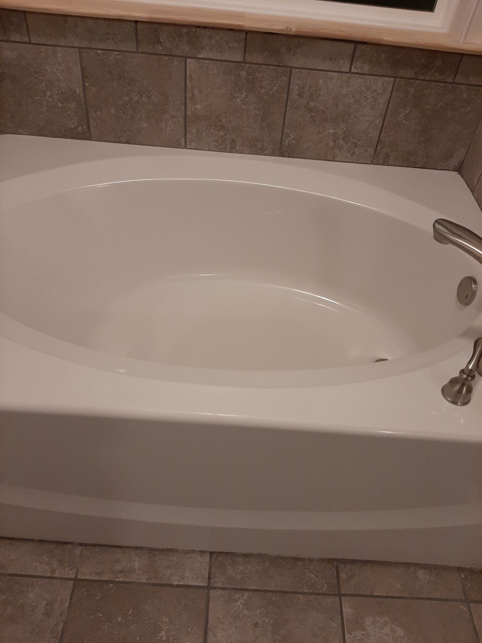 A white bathtub is sitting in a bathroom next to a window.