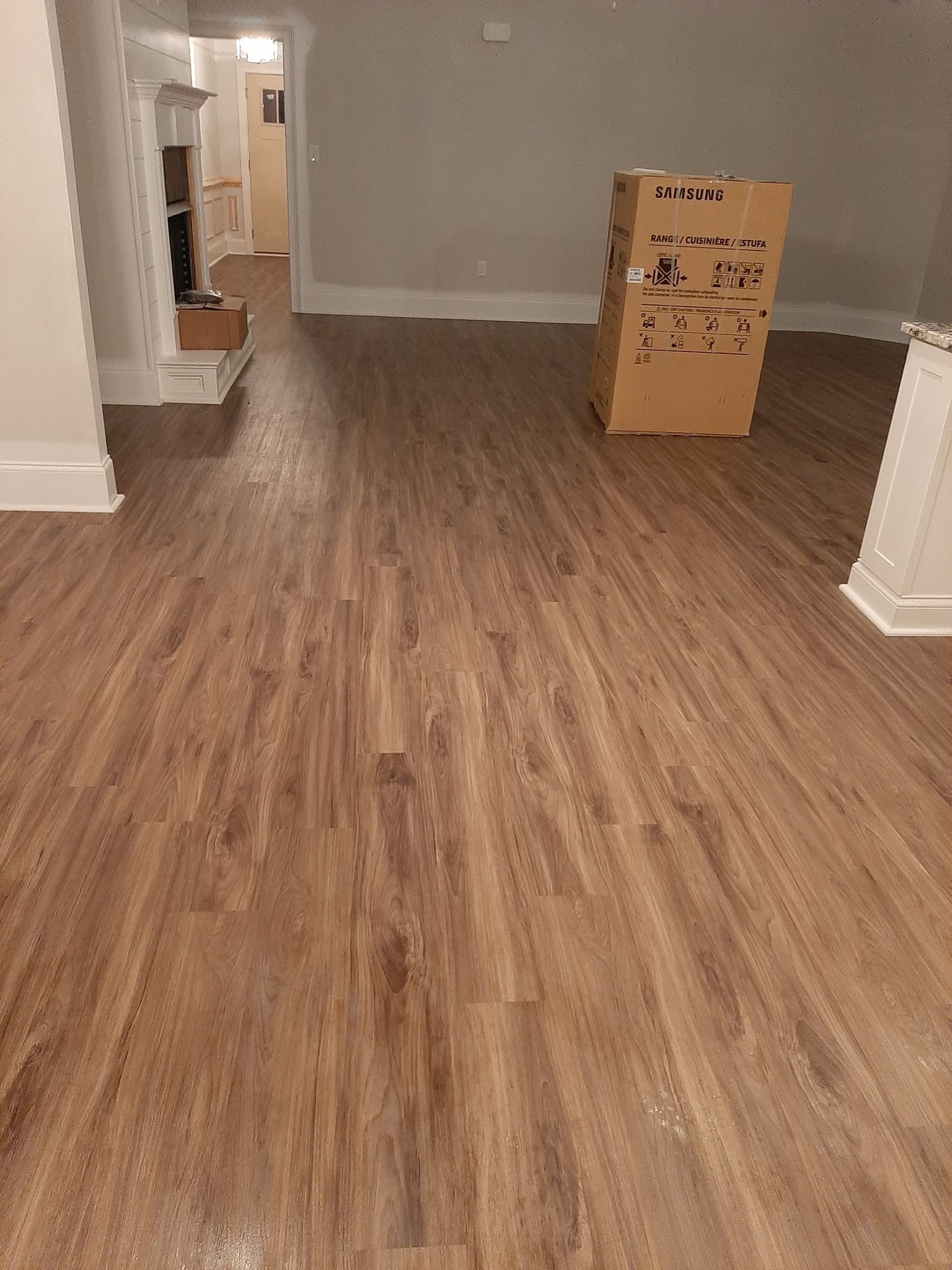 A living room with a wooden floor and a box on the floor.