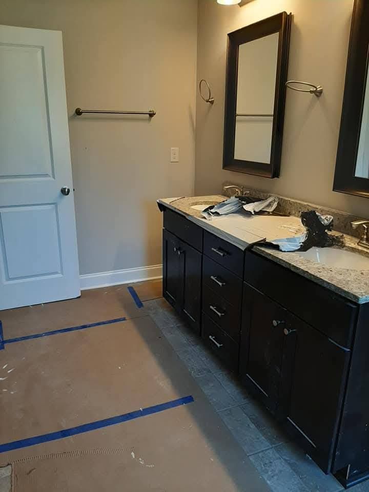 A bathroom with two sinks and two mirrors is being painted.