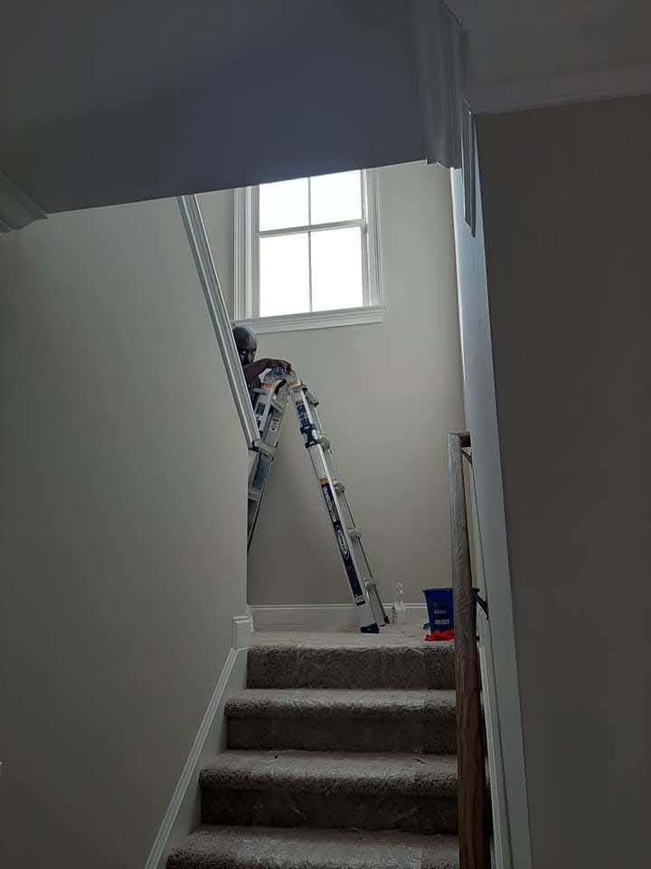 A ladder is sitting on top of a set of stairs next to a window.
