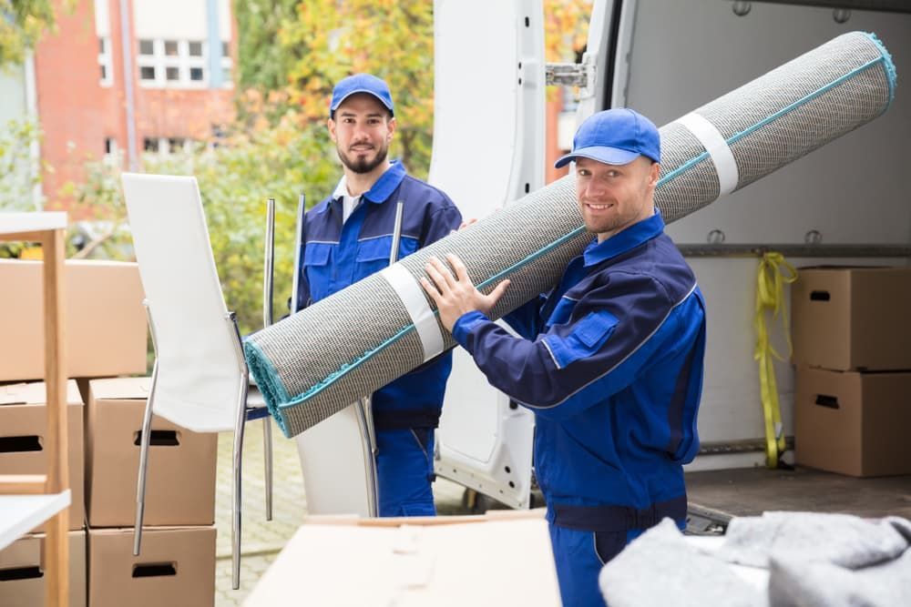 Two Men Are Carrying a Rug in Front of A Van — Lite Moves Furniture Removals In Sunshine Coast, QLD