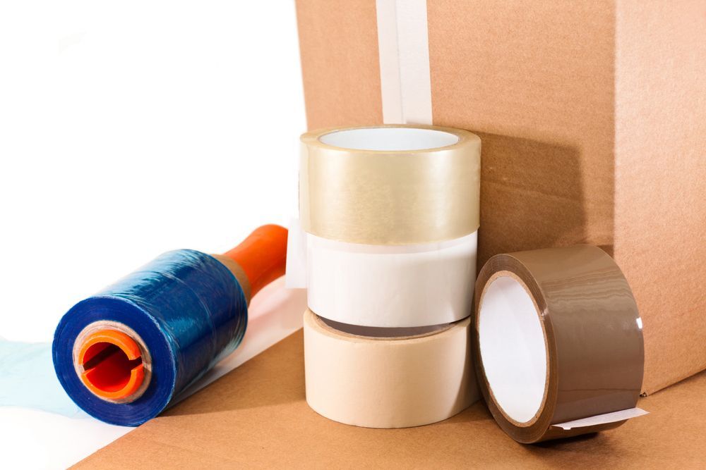 Several Rolls of Tape Are Stacked on Top of Each Other Next to a Cardboard Box — Lite Moves Furniture Removals In Coffs Harbour, NSW