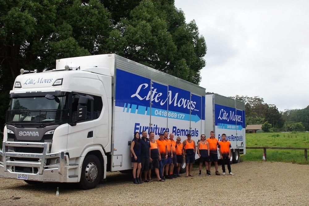 A Group of Movers in Orange Vests Stand in Front Truck — Lite Moves Furniture Removals In Sydney, NSW