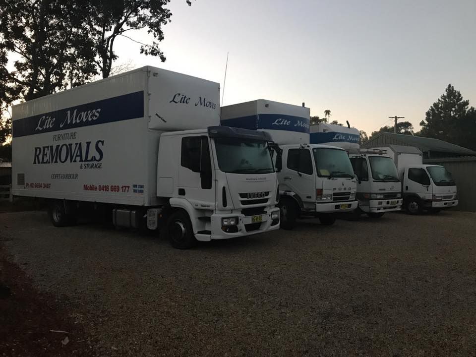 A Row of Moving Trucks Are Parked in A Gravel Lot — Lite Moves Furniture Removals In Bonville, NSW