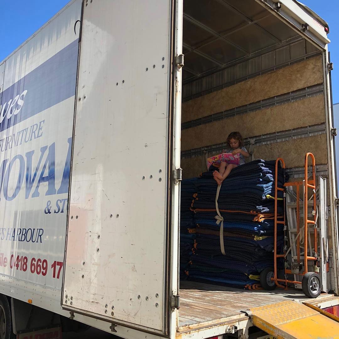 A Little Girl Sits on The Back of A Moving Truck — Lite Moves Furniture Removals In Bonville, NSW