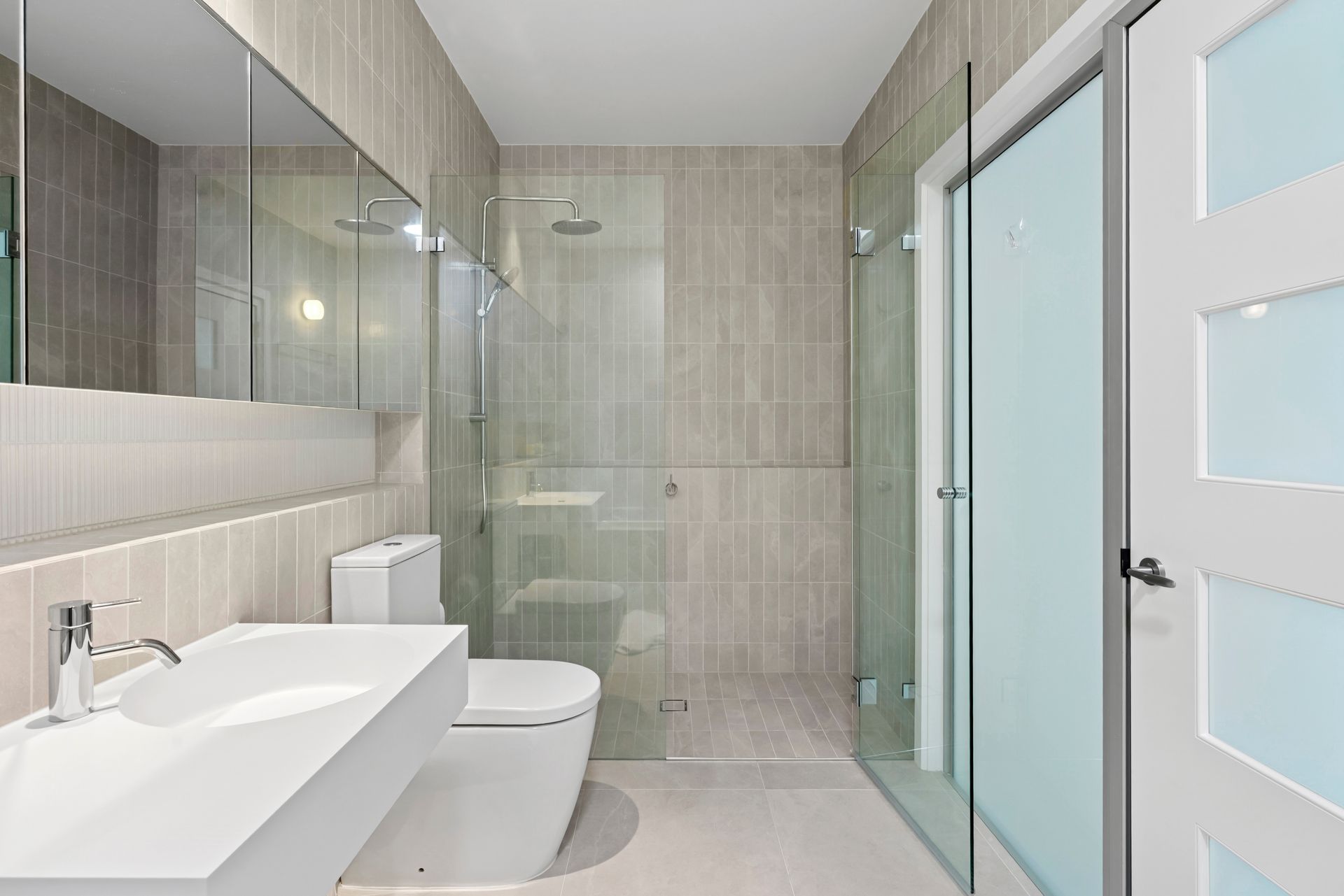 Modern bathroom with a white sink, toilet, and glass shower against gray tiled walls — PK4 Projects in Port Macquarie, NSW