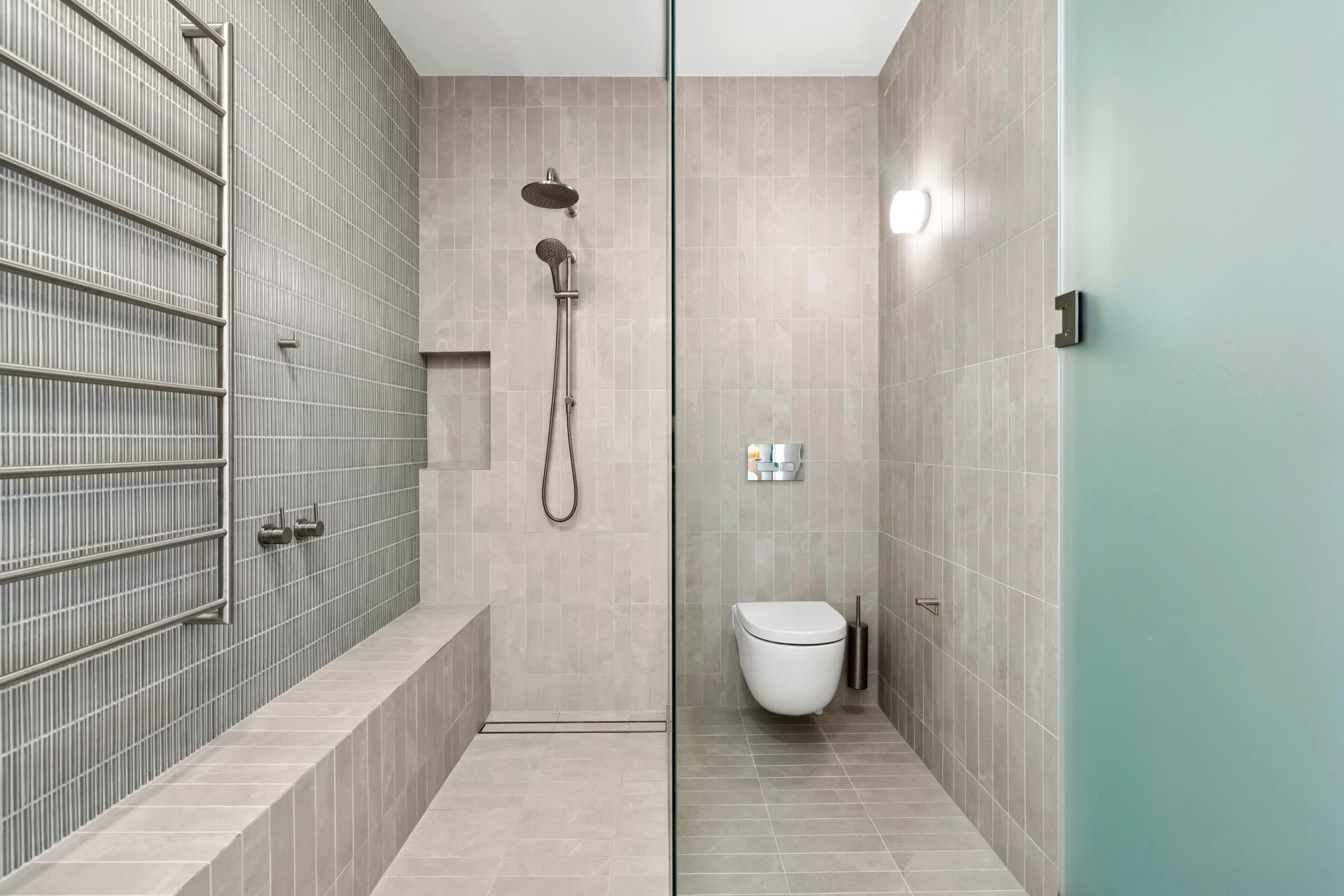 Modern bathroom with gray tiles, glass shower, toilet, and towel warmer. — PK4 Projects in Port Macquarie, NSW