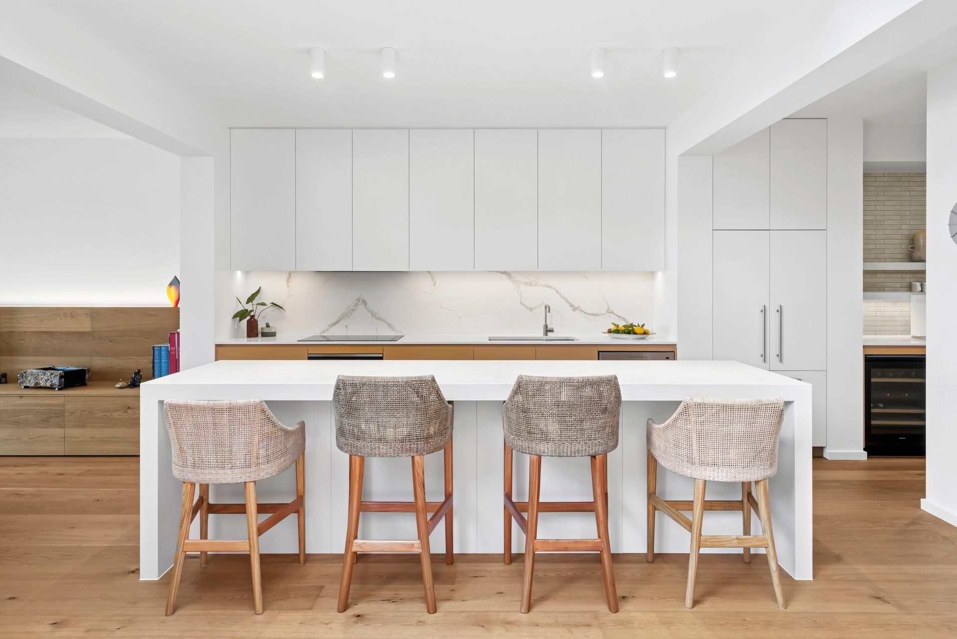 Modern kitchen with white cabinets, island, wooden floor, and four bar stools — PK4 Projects in Port Macquarie, NSW 