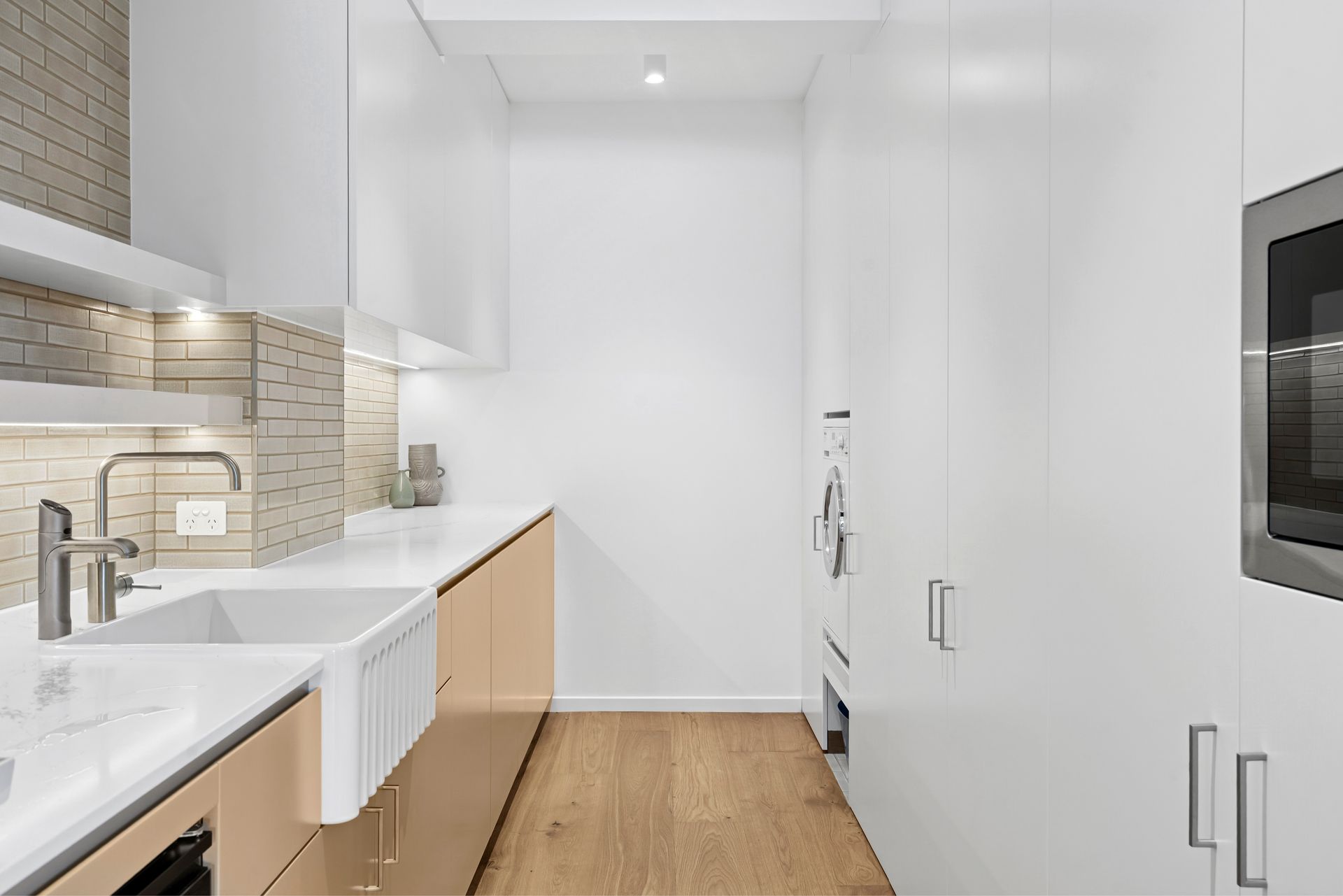 Modern, narrow kitchen with white cabinets, light wood flooring, and stainless steel appliances — PK4 Projects in Port Macquarie, NSW 
