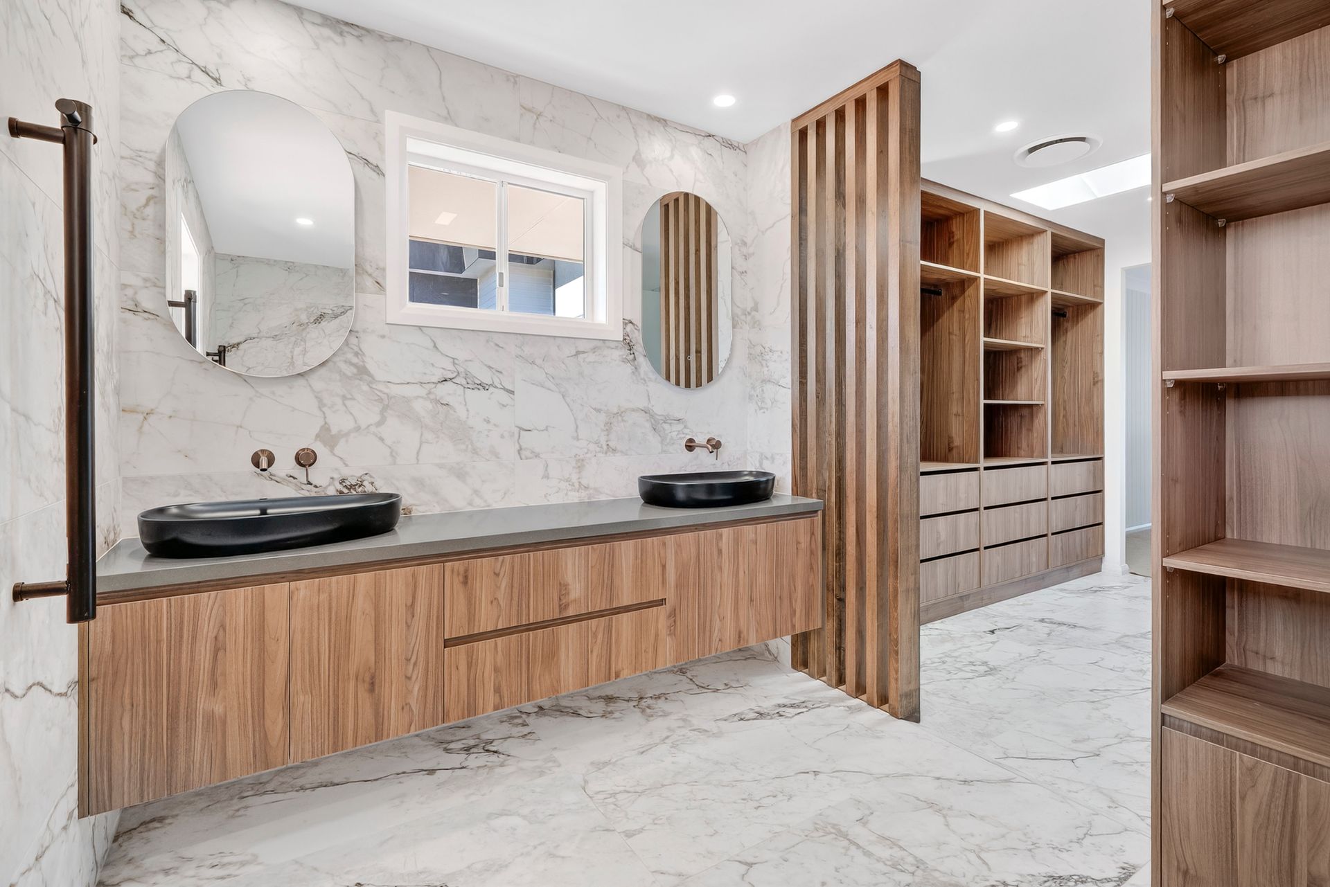 Modern bathroom with marble walls and wood vanity with two sinks and mirrors. Closet in background — PK4 Projects in Port Macquarie, NSW