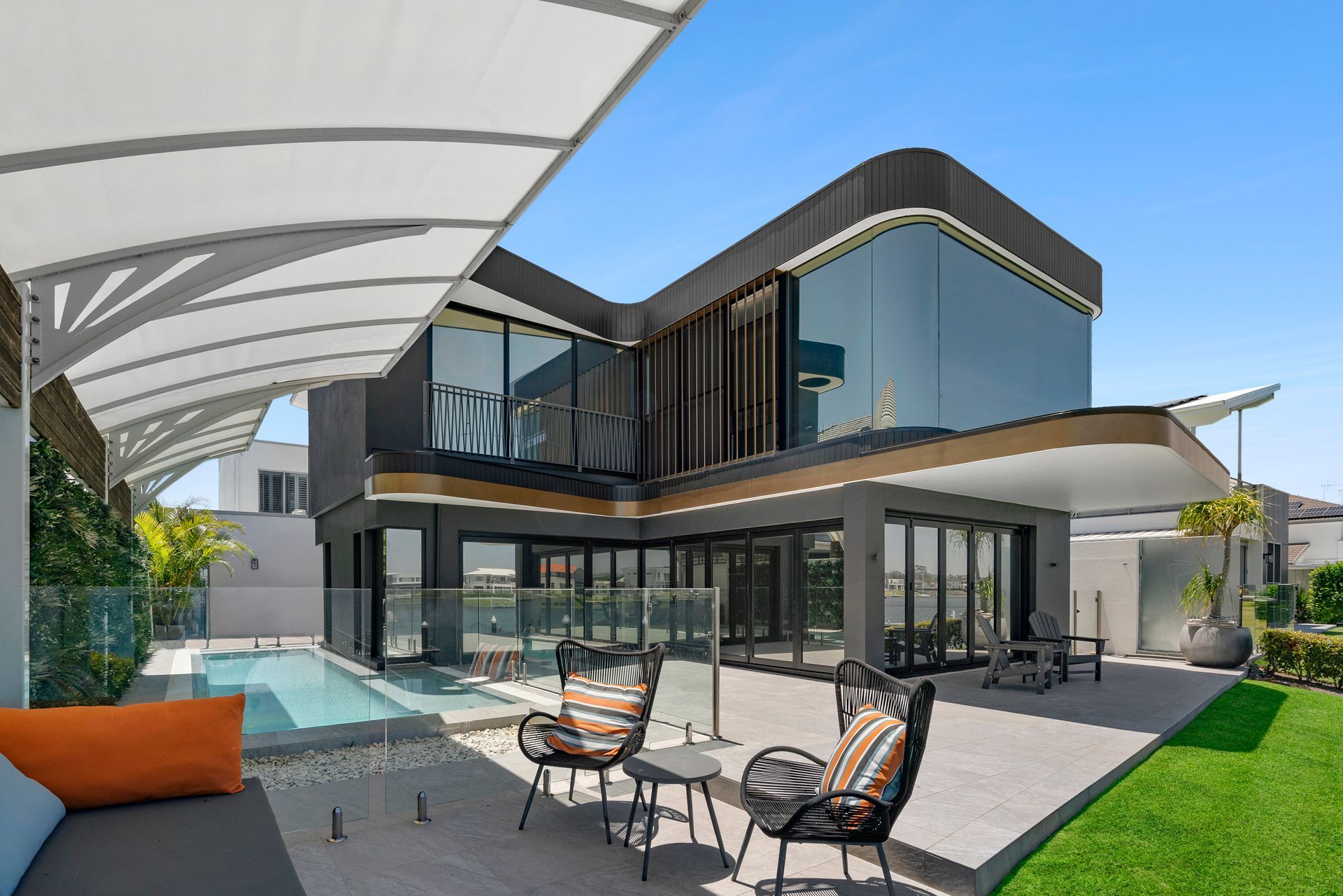 Modern house with pool and outdoor seating. Dark exterior, large windows, blue sky — PK4 Projects in Port Macquarie, NSW
