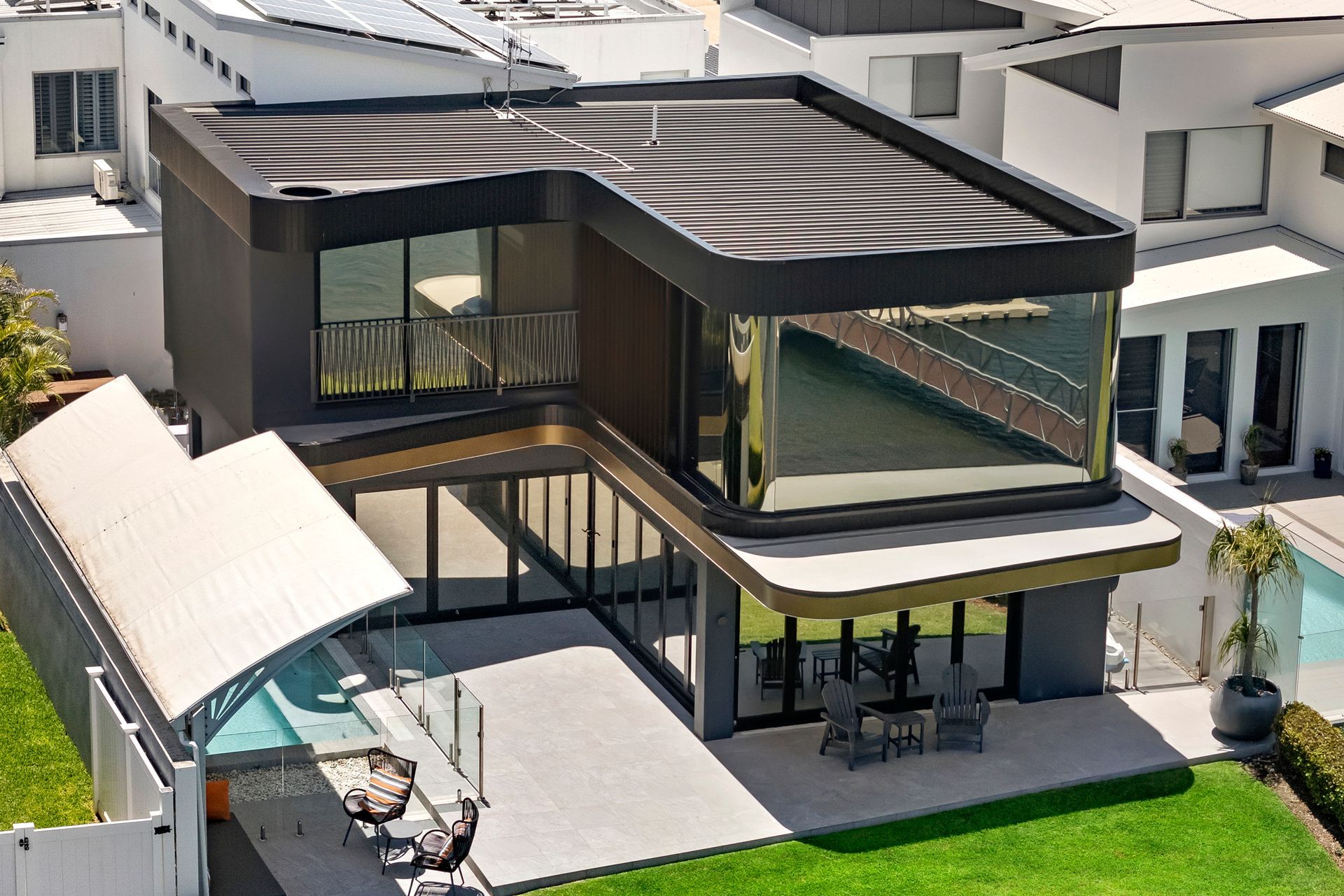 Modern two-story house with black trim, large windows, and an outdoor seating area next to a pool — PK4 Projects in Port Macquarie, NSW