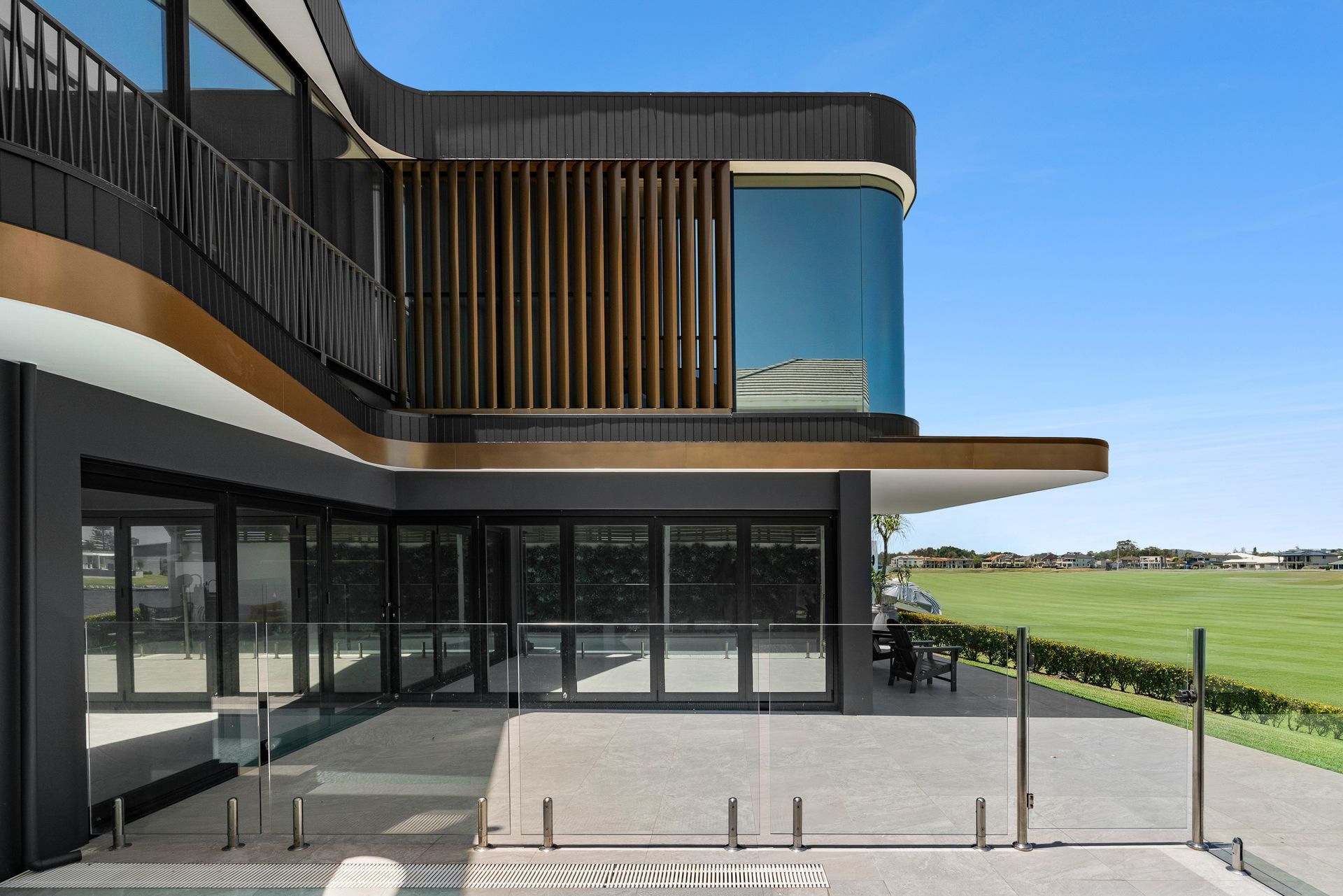 Modern building with curved edges, glass windows, and a patio overlooking a green field under a blue sky — PK4 Projects in Port Macquarie, NSW