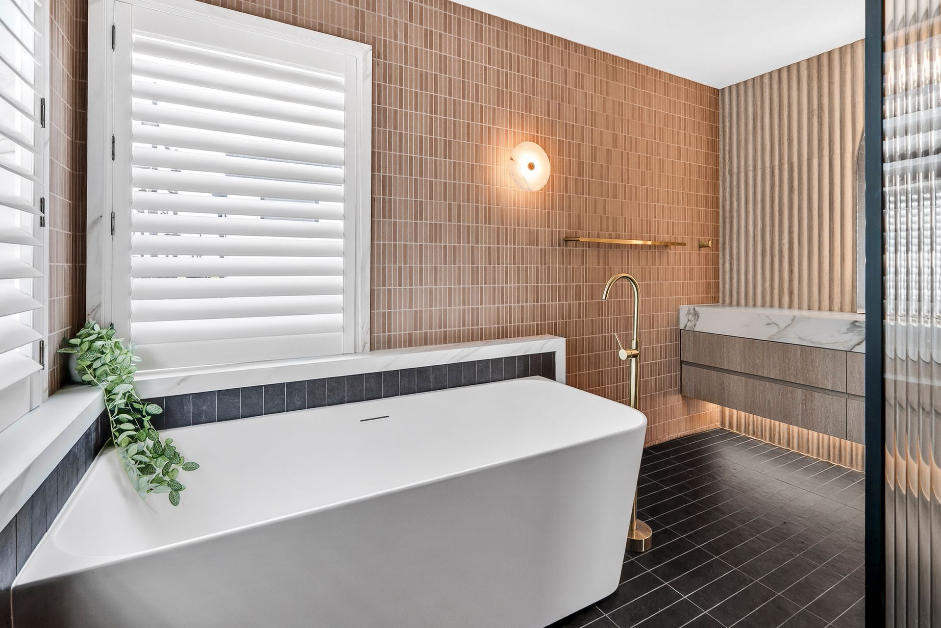 Modern bathroom with white tub, brick wall, window shutters, and black tile floor  — PK4 Projects in Port Macquarie, NSW