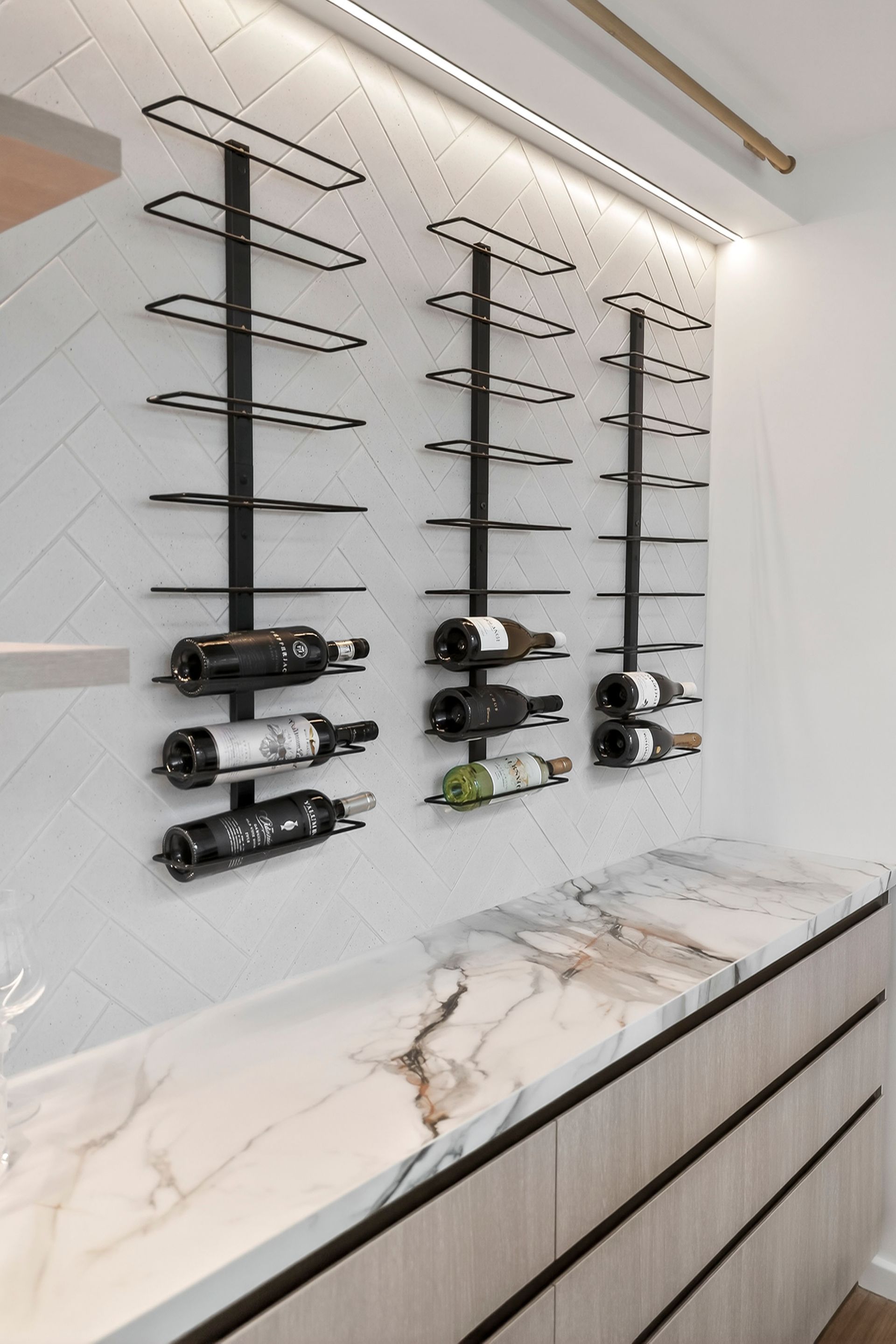 Black wine racks on a white tile wall above a marble countertop and wood cabinets. — PK4 Projects in Port Macquarie, NSW