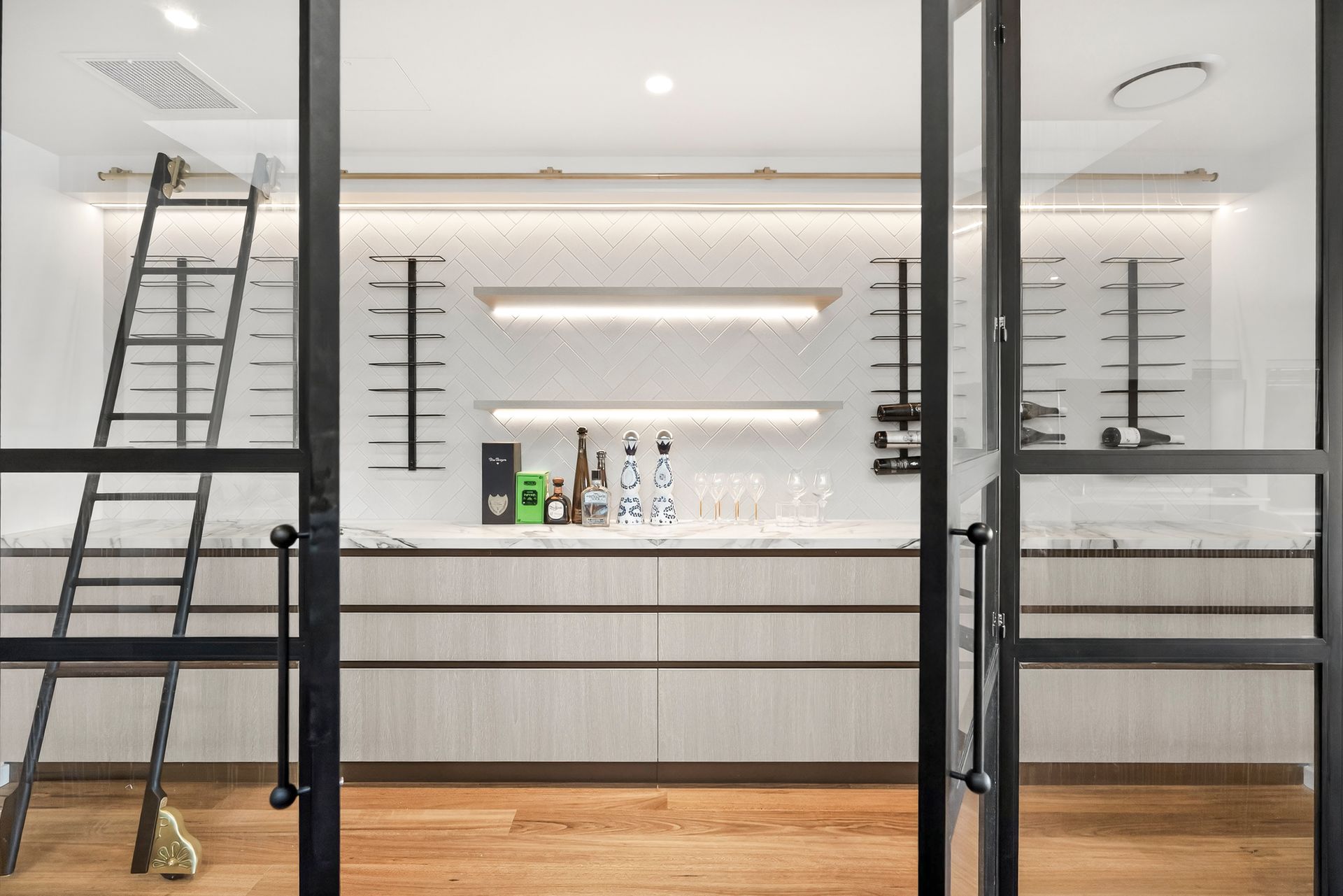 Wine cellar with glass doors, ladder, and wooden floor. Displays bottles and glasses. — PK4 Projects in Port Macquarie, NSW
