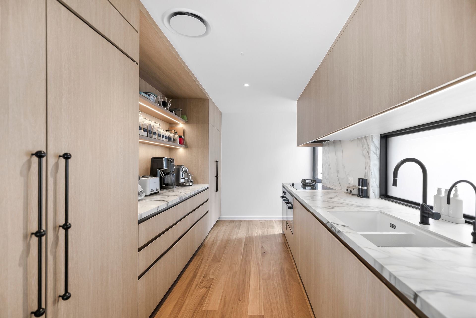 Narrow modern kitchen with light wood cabinets, marble countertops, and black fixtures. — PK4 Projects in Port Macquarie, NSW