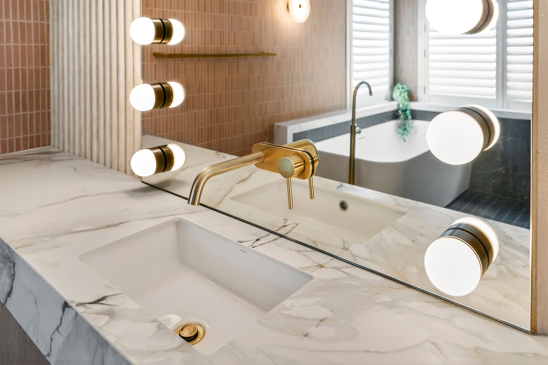 Luxurious bathroom with marble countertop, gold faucet, and circular lights around a large mirror  — PK4 Projects in Port Macquarie, NSW