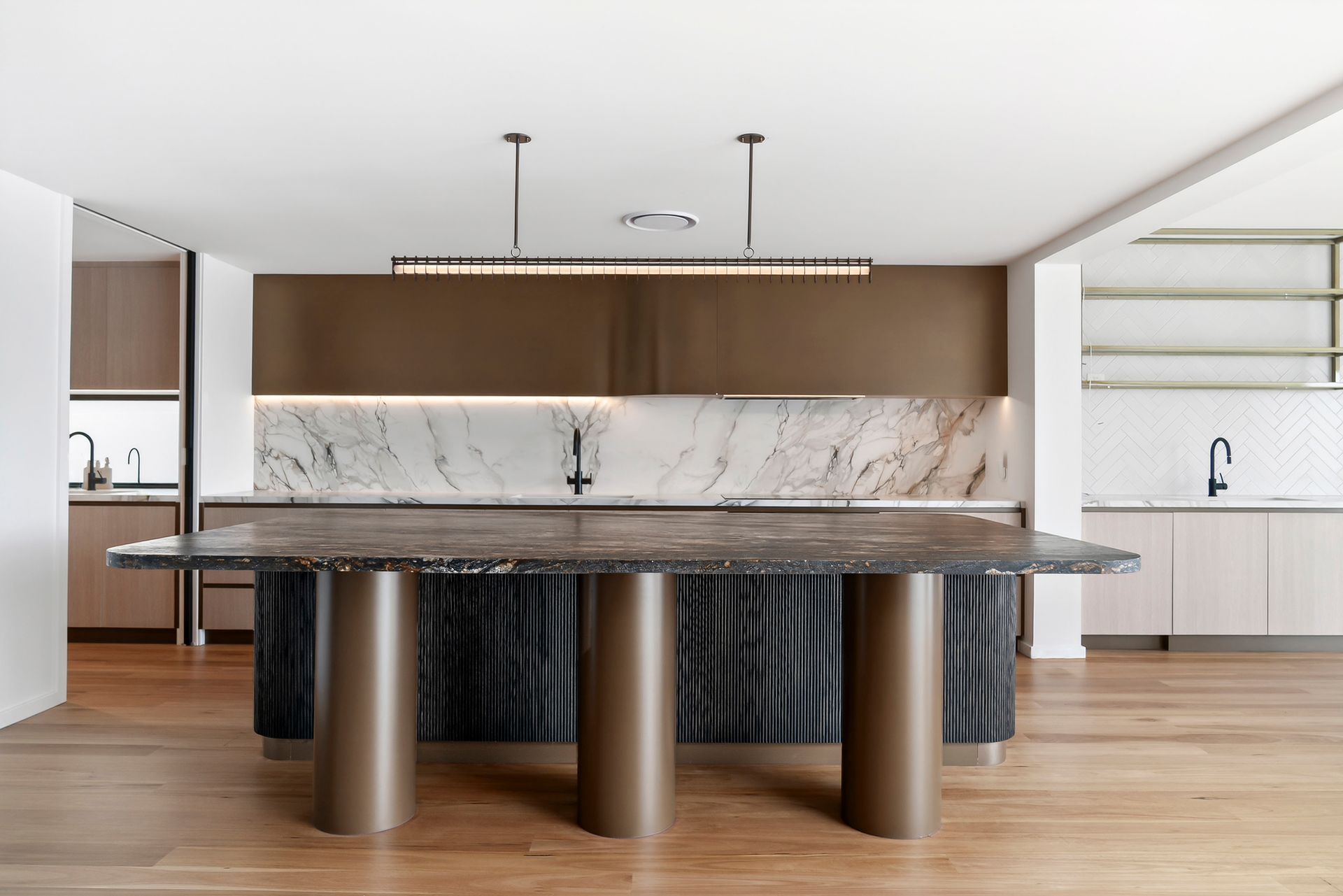 Modern kitchen with island, marble countertops, brown and black cabinets, and wood flooring. — PK4 Projects in Port Macquarie, NSW
