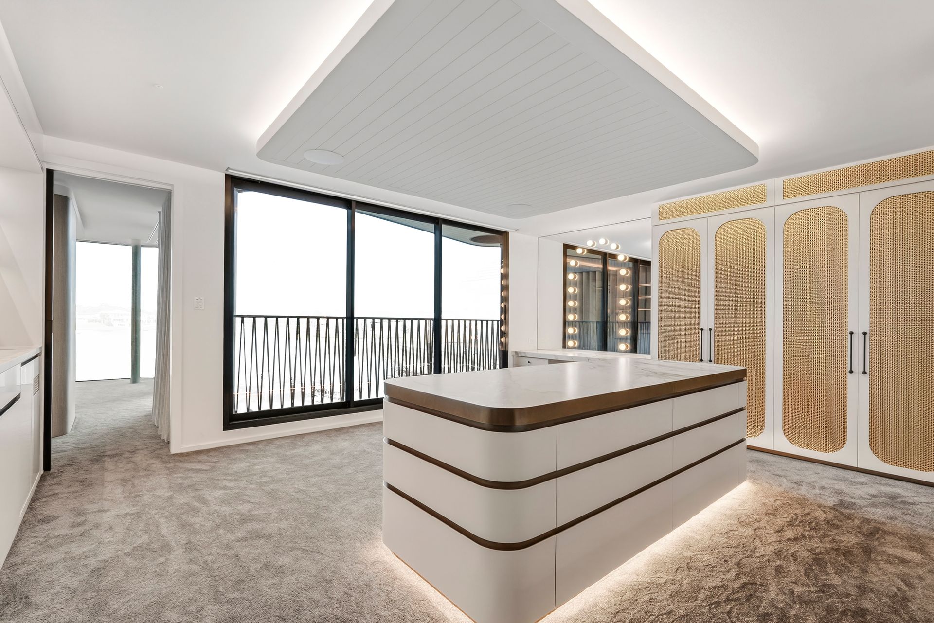 Luxury walk-in closet with island, gold accents, large window, and light-colored carpet — PK4 Projects in Port Macquarie, NSW