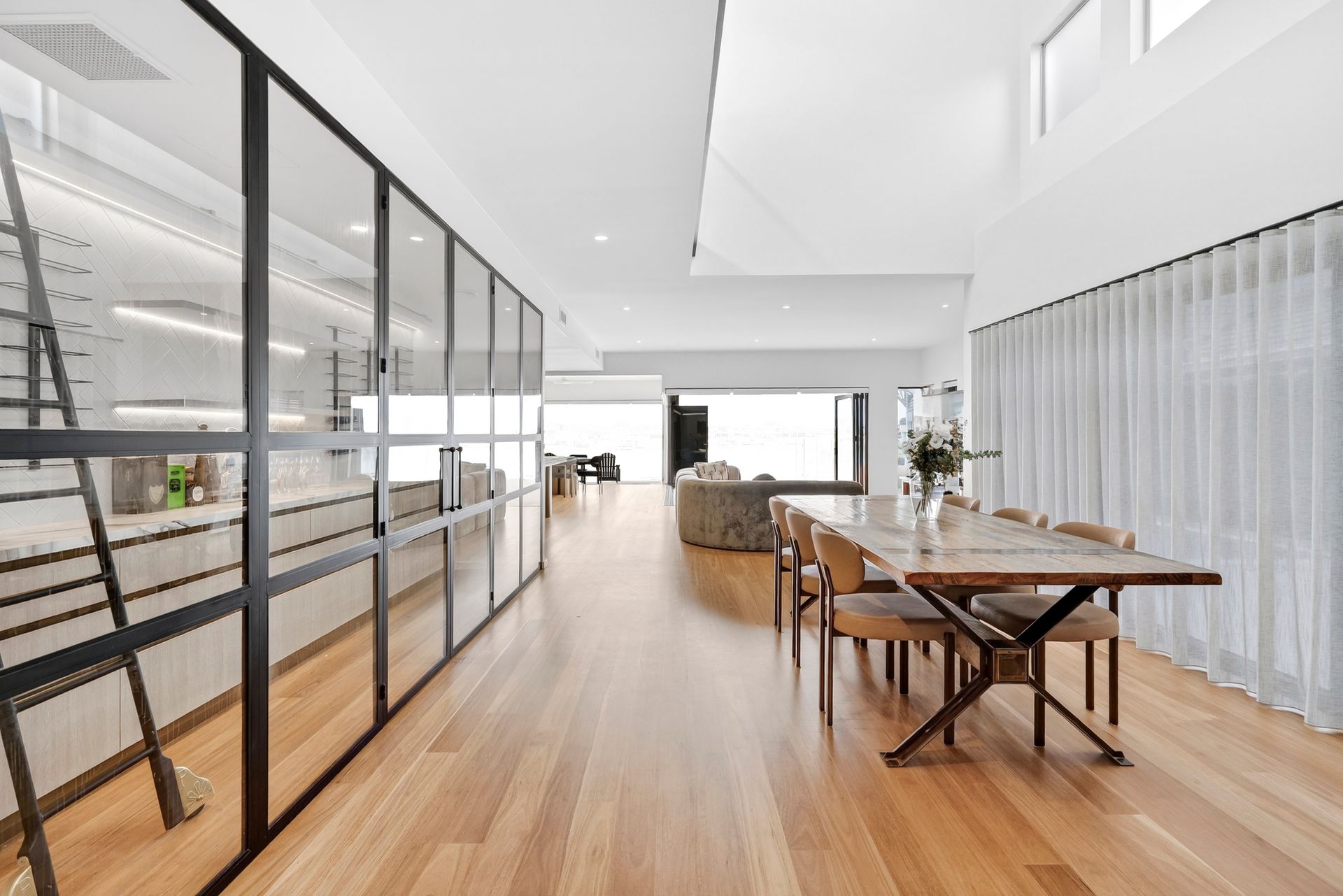 Modern kitchen with glass wall, dining table, and wooden floor. Bright, open space — PK4 Projects in Port Macquarie, NSW