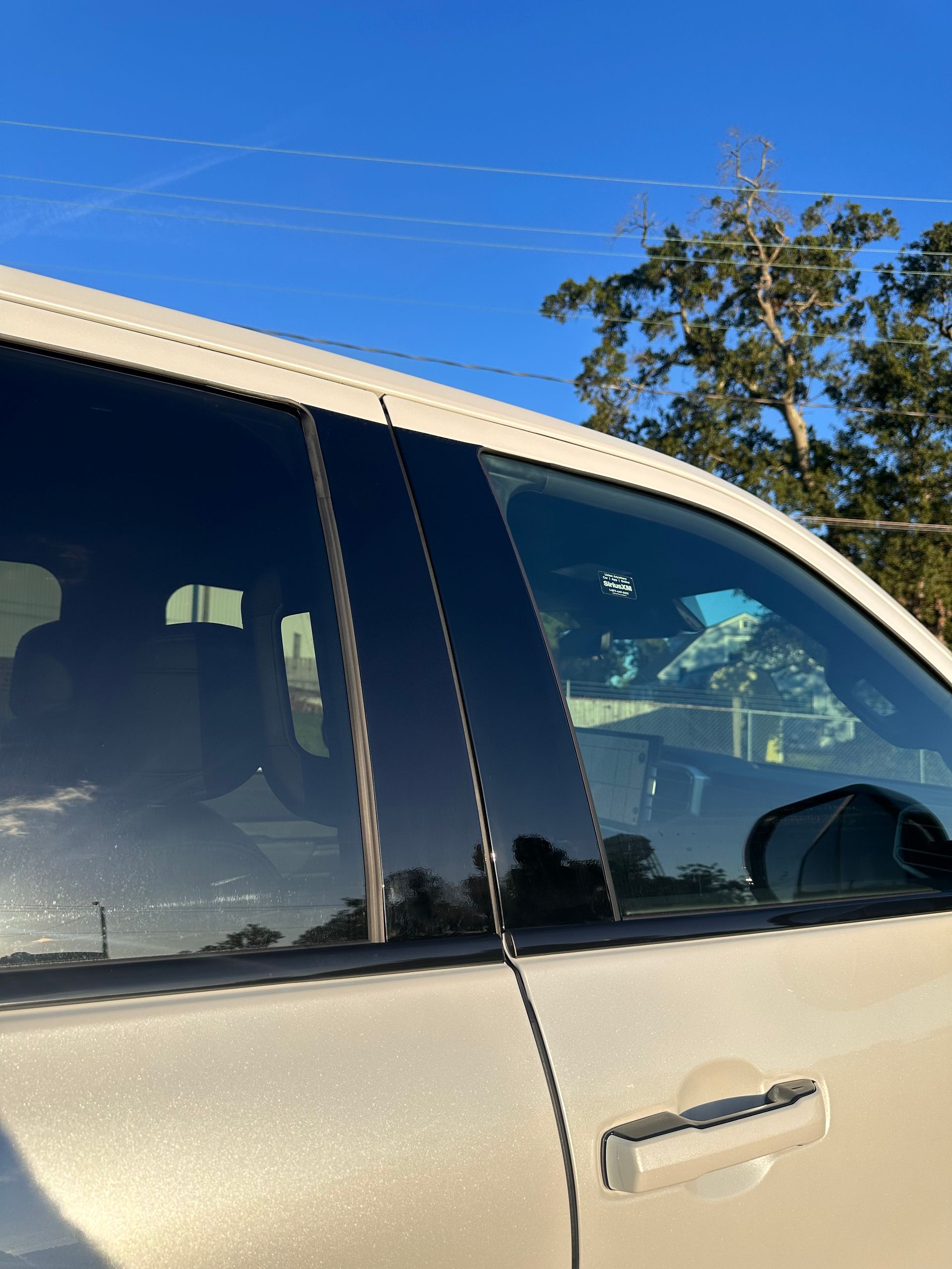 Side view of a beige SUV with tinted windows against a bright blue sky.