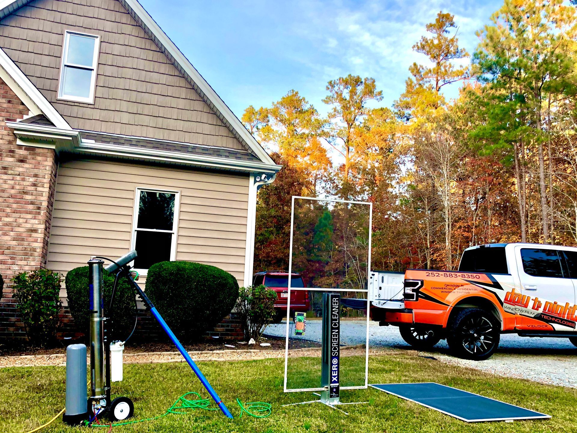 A service vehicle and equipment set up on a lawn in front of a house, likely for utility work.