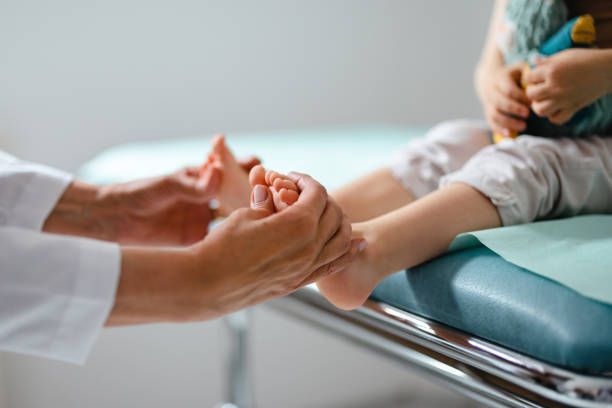 A doctor is examining a child 's foot in a hospital.