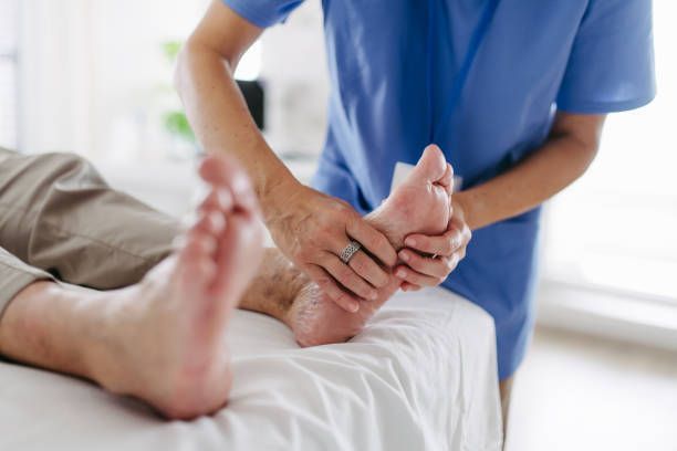 A nurse is massaging a patient 's foot on a bed.
