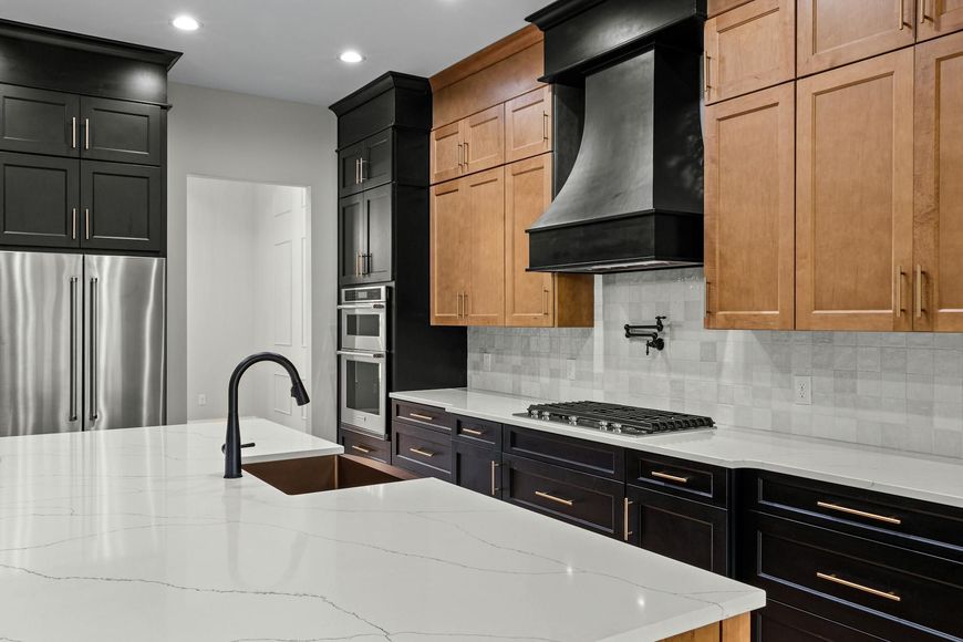 A kitchen with wooden cabinets , stainless steel appliances , a sink , and a stove top oven.