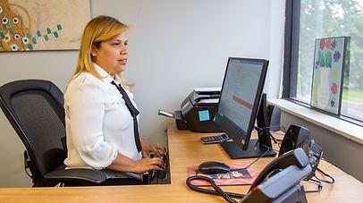 Woman with blonde hair, typing at a desk in an office.