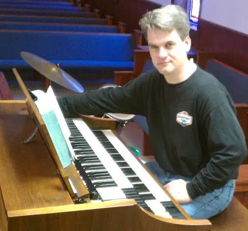 A man in a black shirt is playing an organ