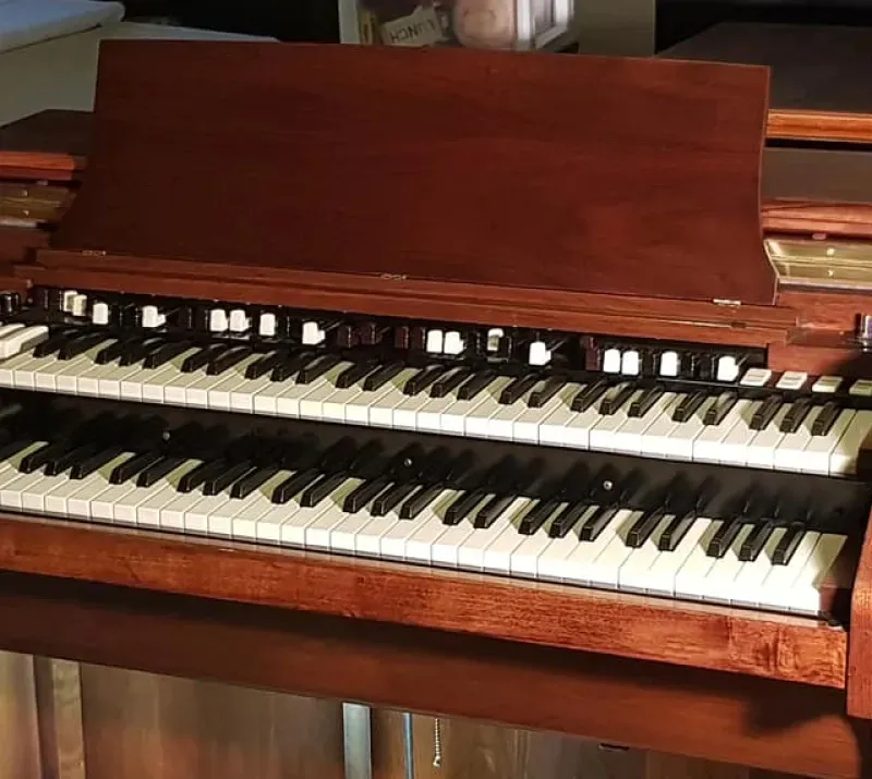 A double keyboard organ is sitting on a wooden table.