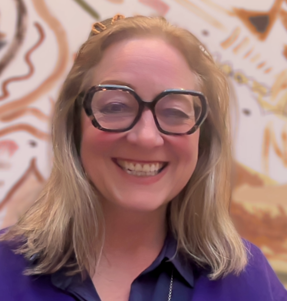 A woman in a black coat is standing in front of a bridge.