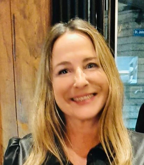 A woman with long blonde hair is smiling for the camera.