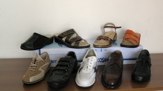 Assortimento di scarpe eleganti e mocassini nei colori beige, nero, bianco, marrone e arancione, esposti su due file.