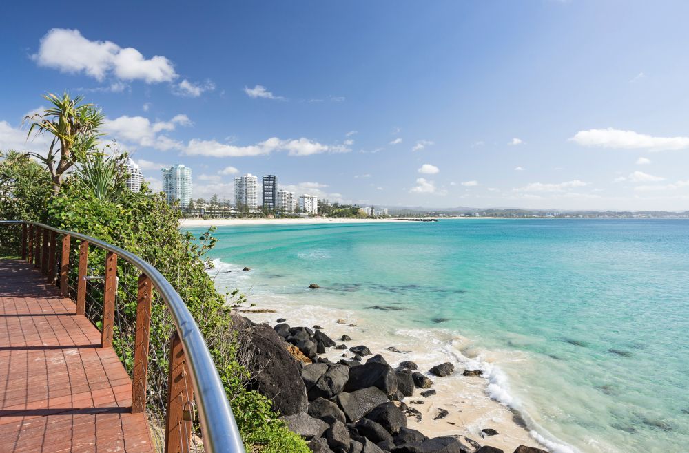 A Walkway Leading To A Beach With A City In The Background — Sampson Plumbing Pty Ltd In Burleigh Heads, QLD