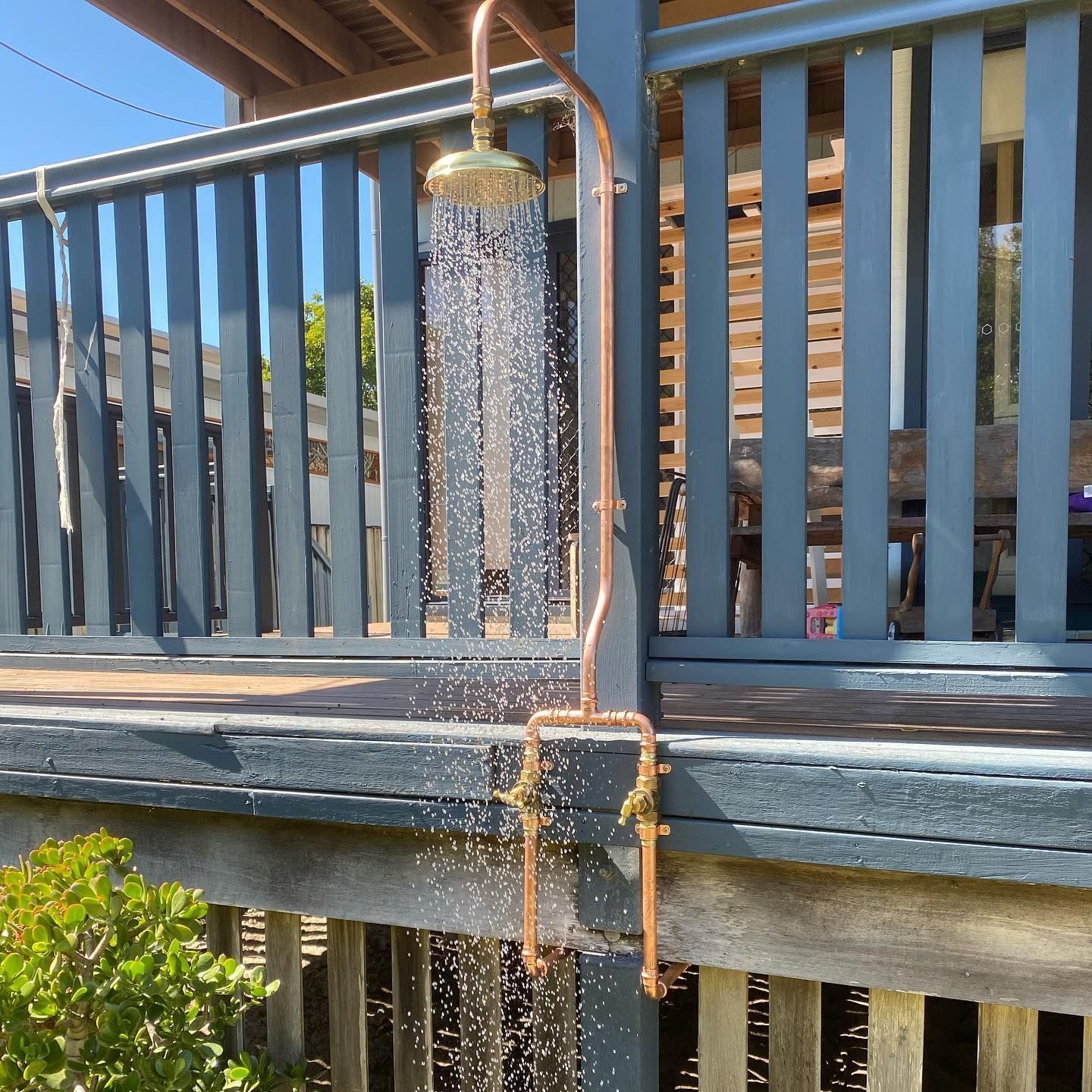 A Gold Outdoor Shower Has Water Flowing From It — Sampson Plumbing Pty Ltd In Casuarina, NSW
