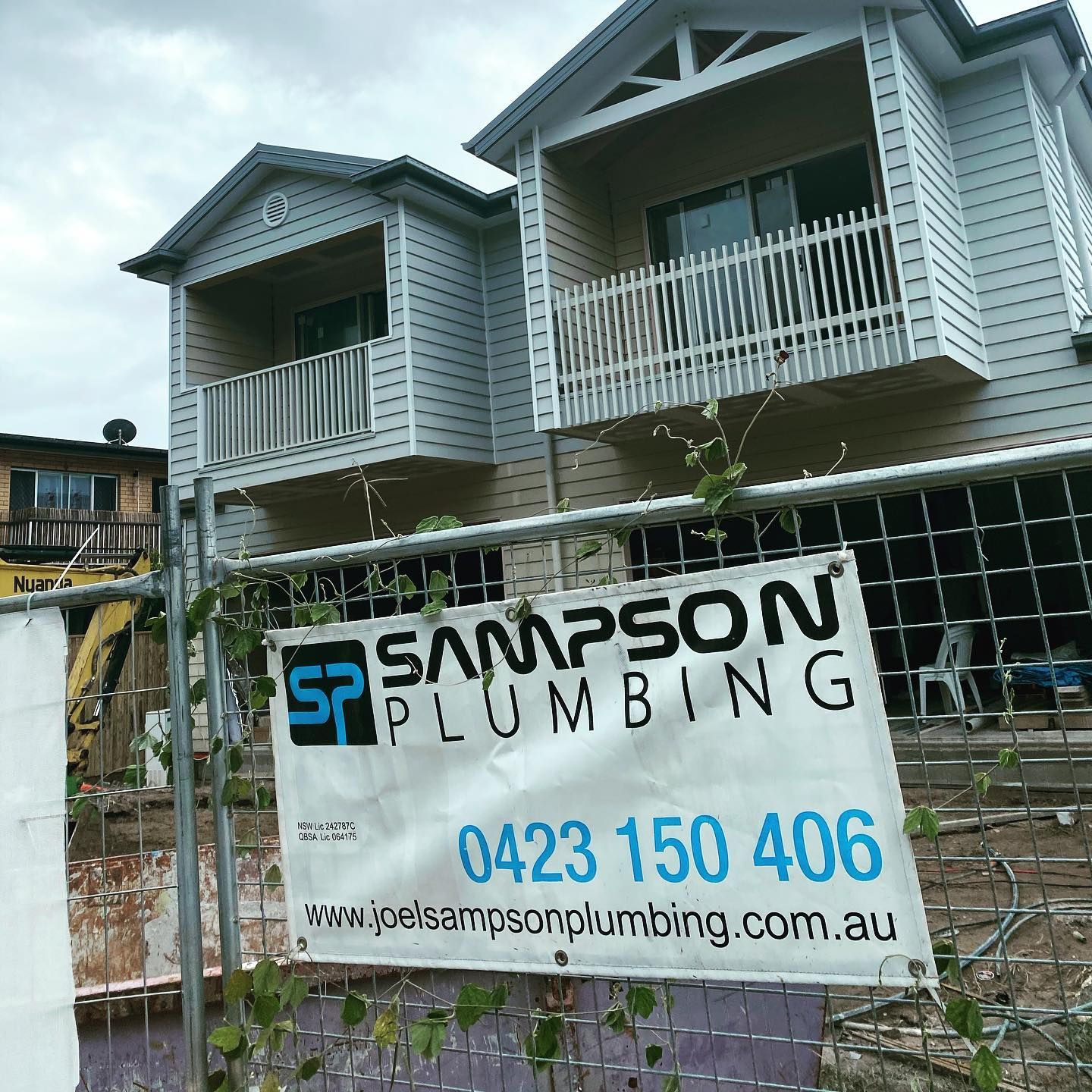 A Sampson Plumbing Sign Is On A Fence In Front Of A House — Sampson Plumbing Pty Ltd In Casuarina, NSW