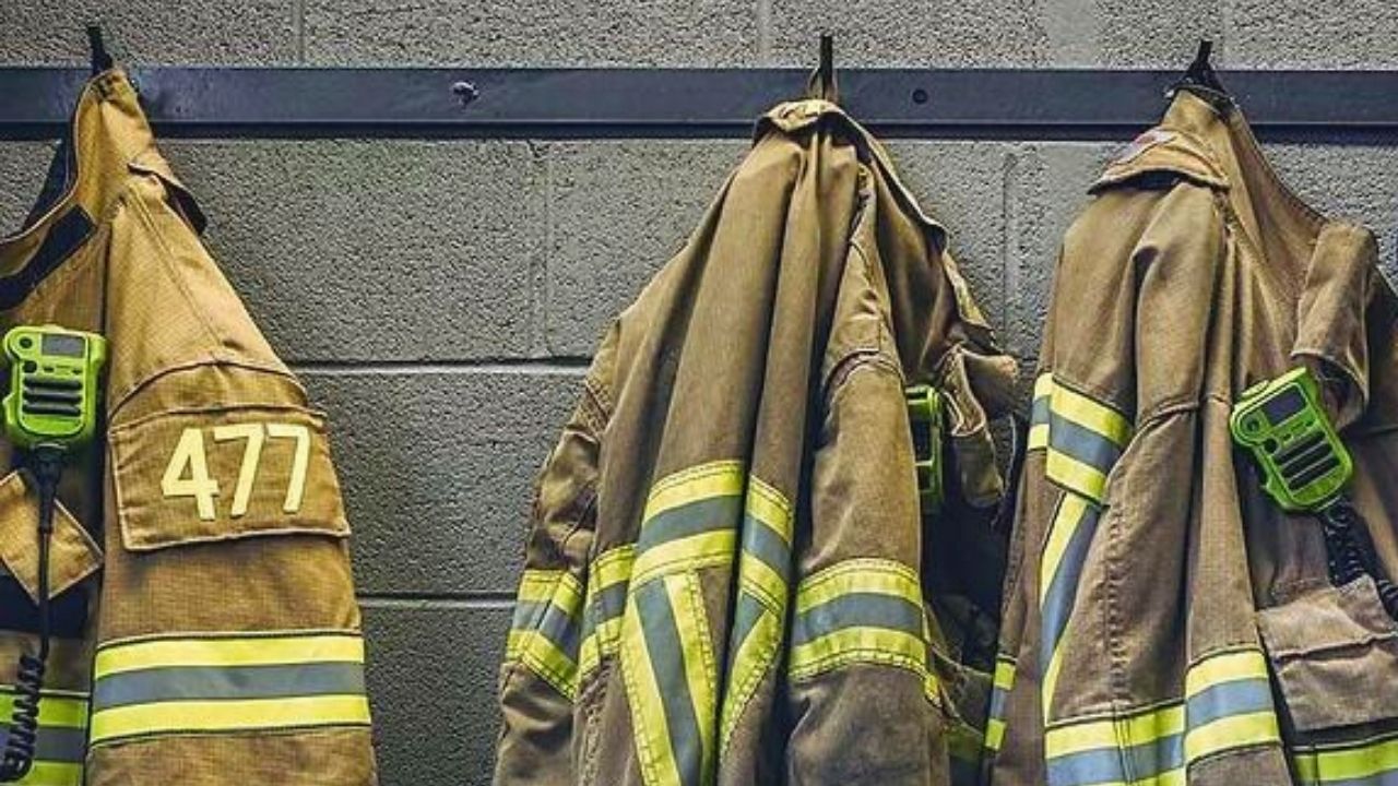 A row of firefighter jackets hanging on a wall.