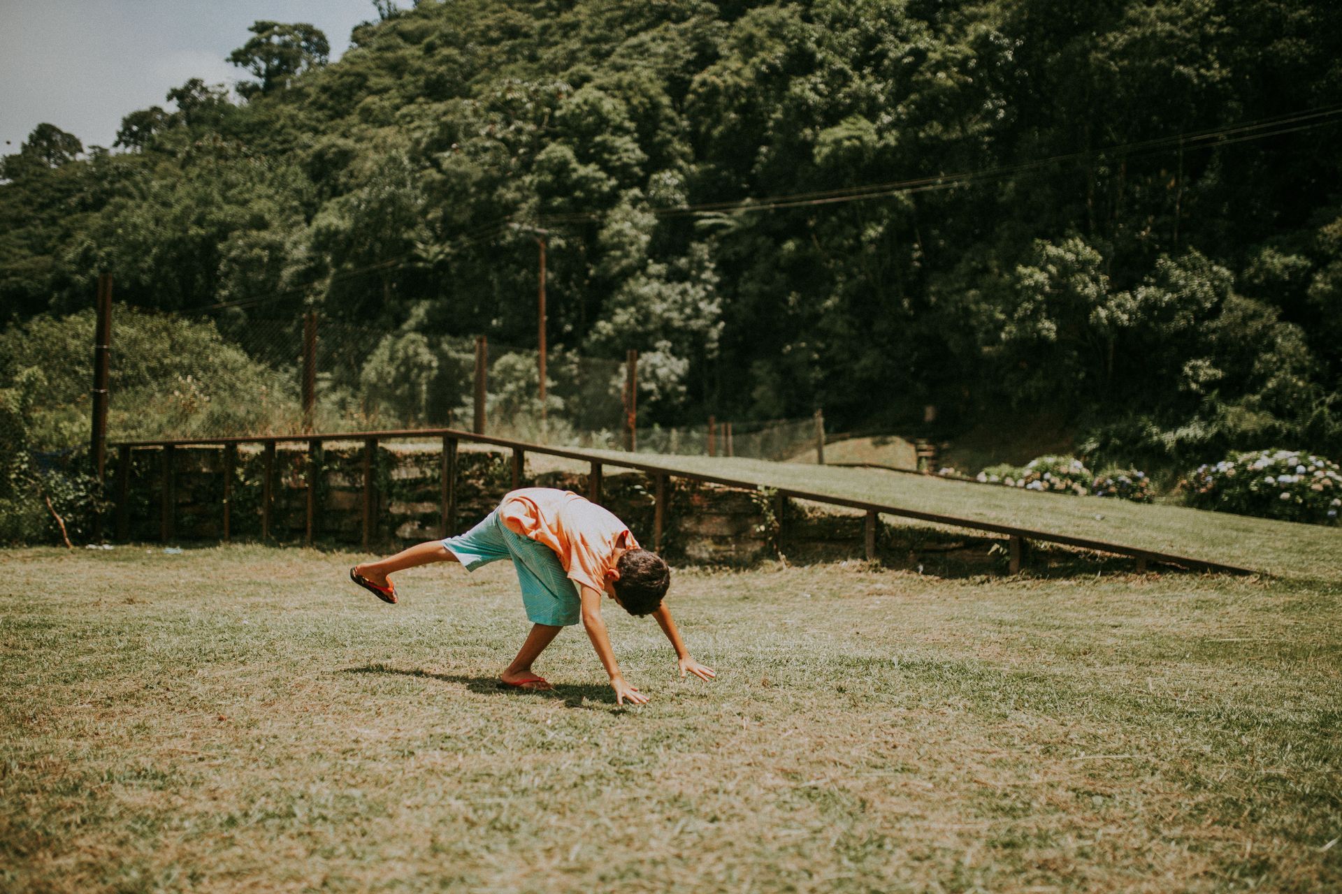 A boy doing cartwheels in a park on a summers day.