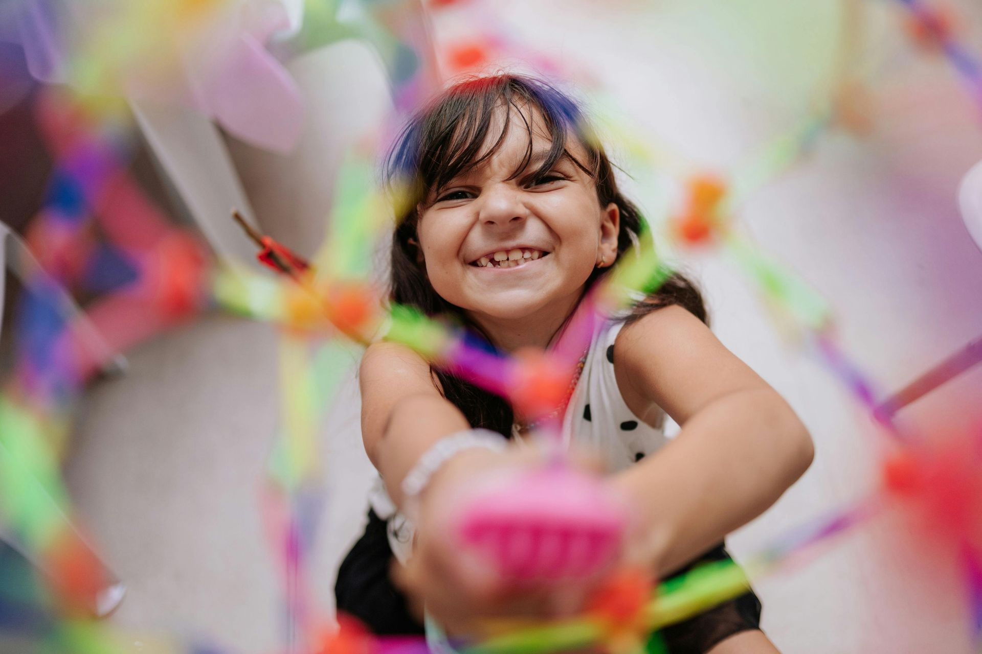Smiling child reaching toward colorful confetti in a festive scene