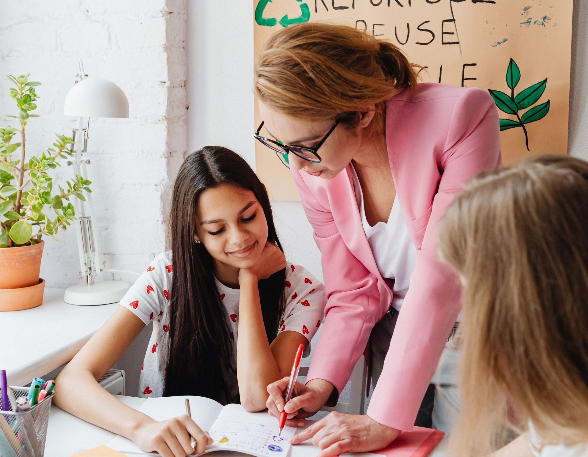 Teacher helping two students with a worksheet in a bright classroom