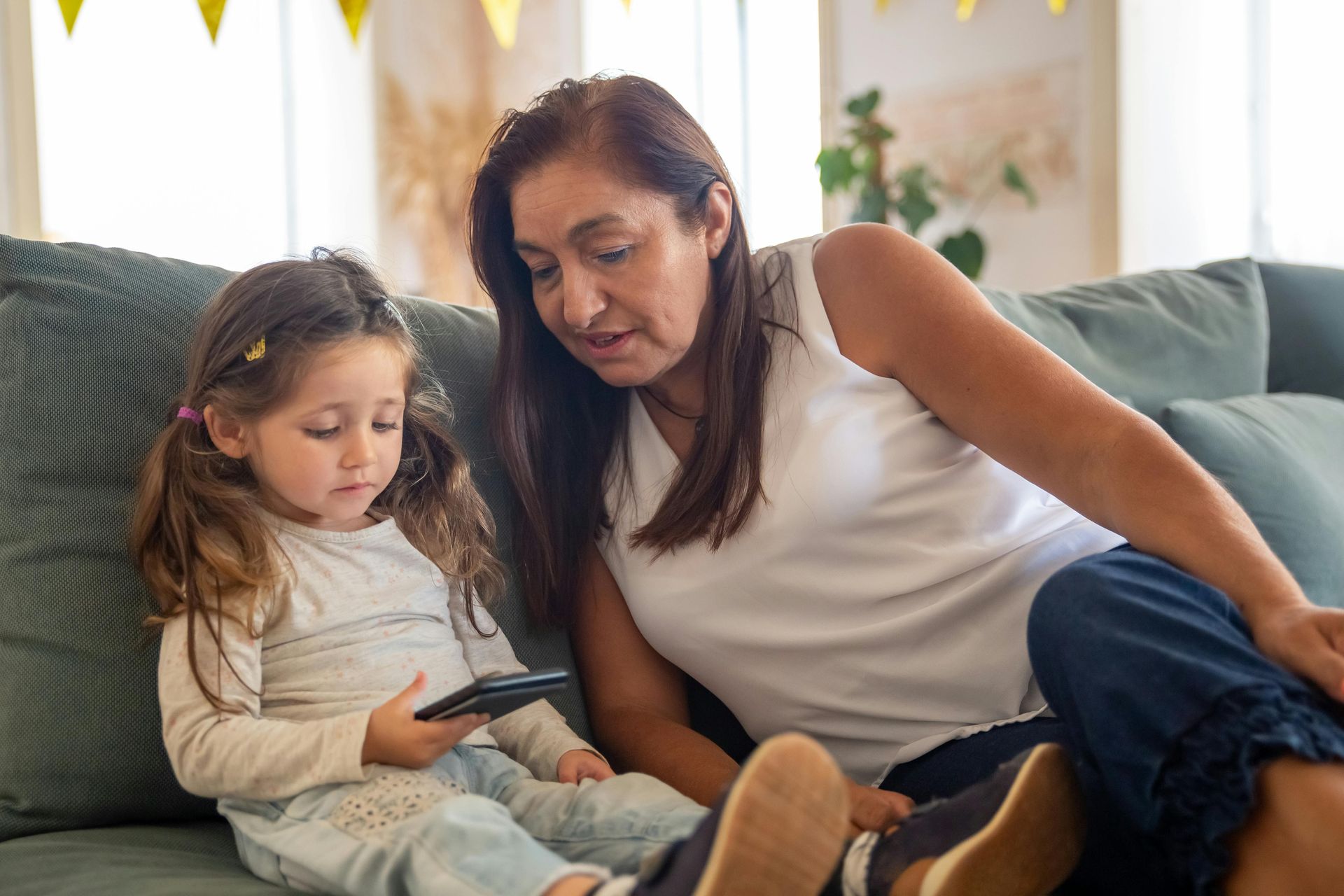Woman and child on couch looking at a phone screen.
