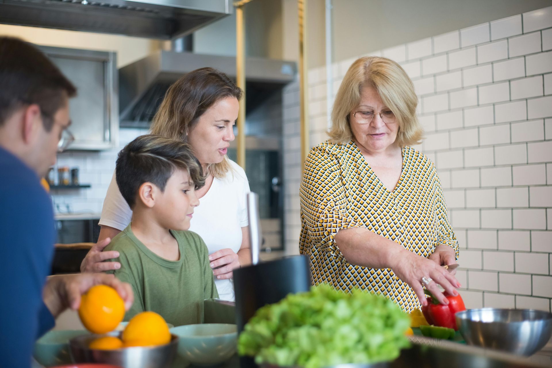 Family cooking together in a kitchen, cutting vegetables and preparing food.