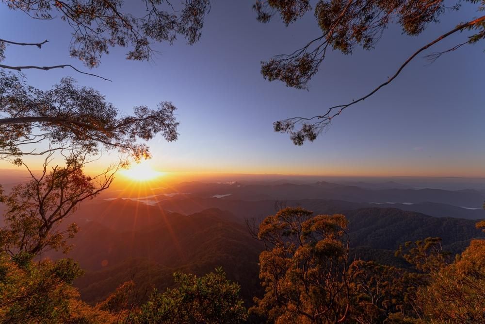 The Sun is Setting Over a Mountain Range with Trees in the Foreground — Bakery Equipment in New England, NSW