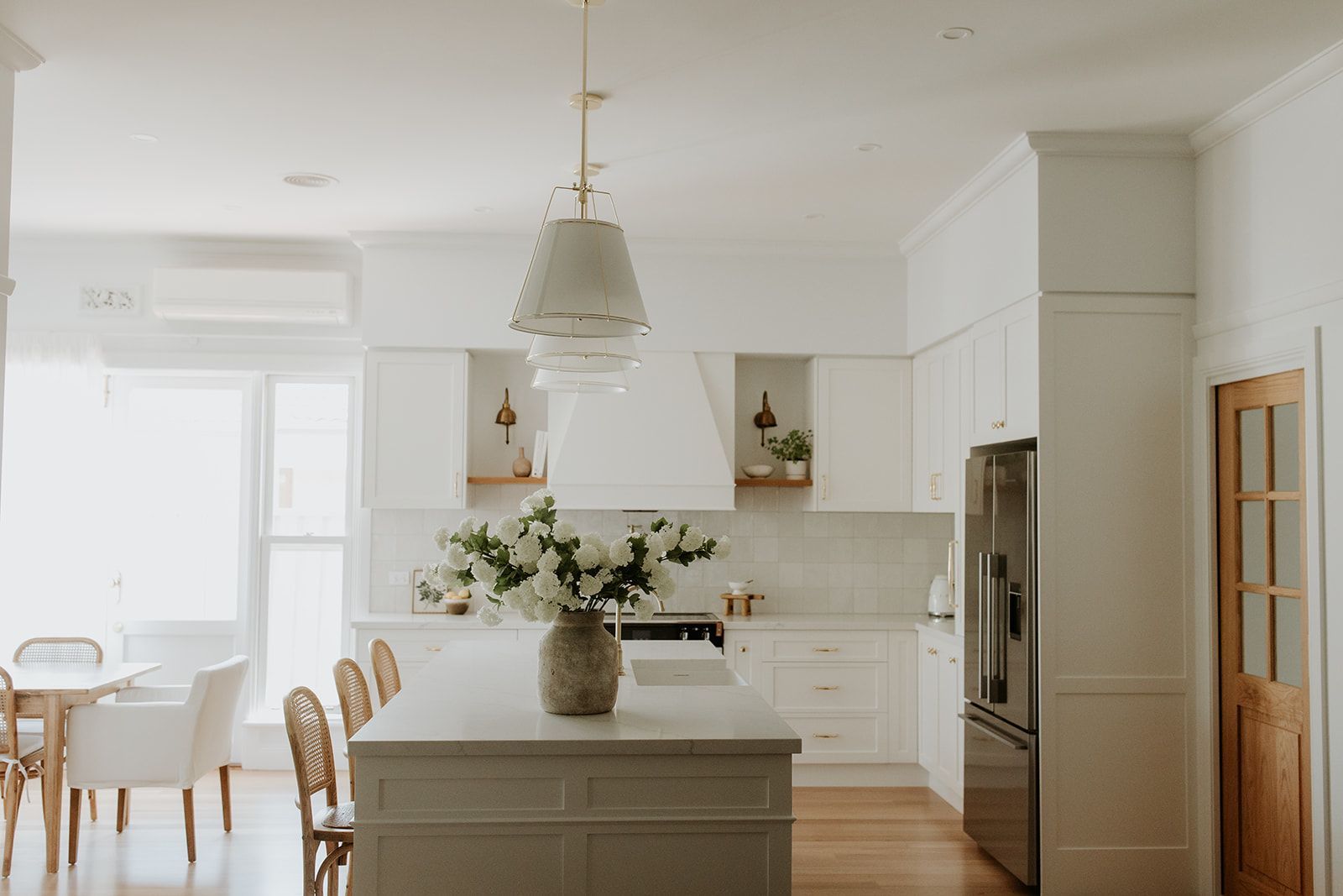 A white kitchen island with stone benchtop and breakfast bar seating by KitchenWise in Shepparton.