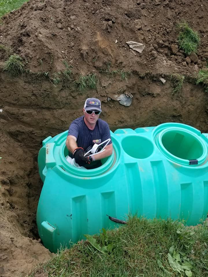 A man is sitting inside of a green septic tank.