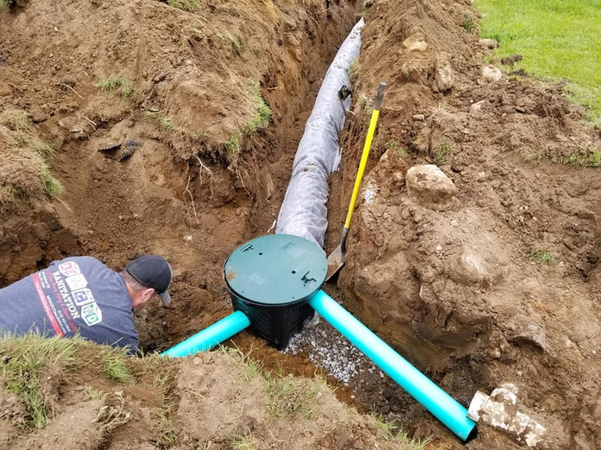 A man is working on a septic system in the dirt.