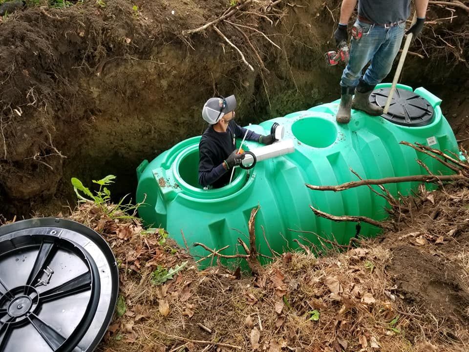 A man is standing on top of a green septic tank.